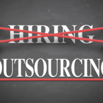 Two hands cross out the word "HIRING" with red lines and highlight the word "OUTSOURCING" in bold white letters on a chalkboard background.