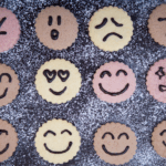 Assorted cookies decorated with emoji-style faces showing different emotions, symbolizing the variety of human feelings.